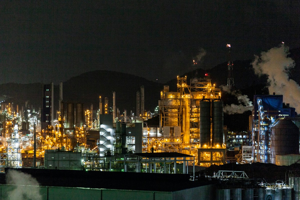 Illustrative night view of a large petrochemical industrial complex with lit processing structures