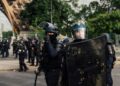 Riot police officers holding shields in an urban street, used as contextual imagery for France's recent unrest.