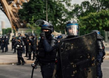 Riot police officers holding shields in an urban street, used as contextual imagery for France's recent unrest.