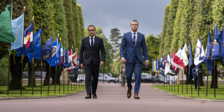 French Prime Minister Sébastien Lecornu walking alongside U.S. Defense Secretary Pete Hegseth during a ceremony in Normandy in June 2025.